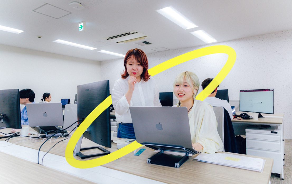 オフィスでノートPCを見ながら打ち合わせする2人の社員